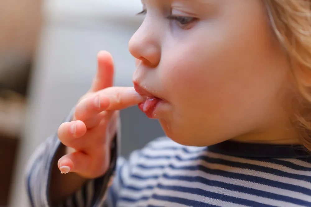 Kind steckt Finger in den Mund